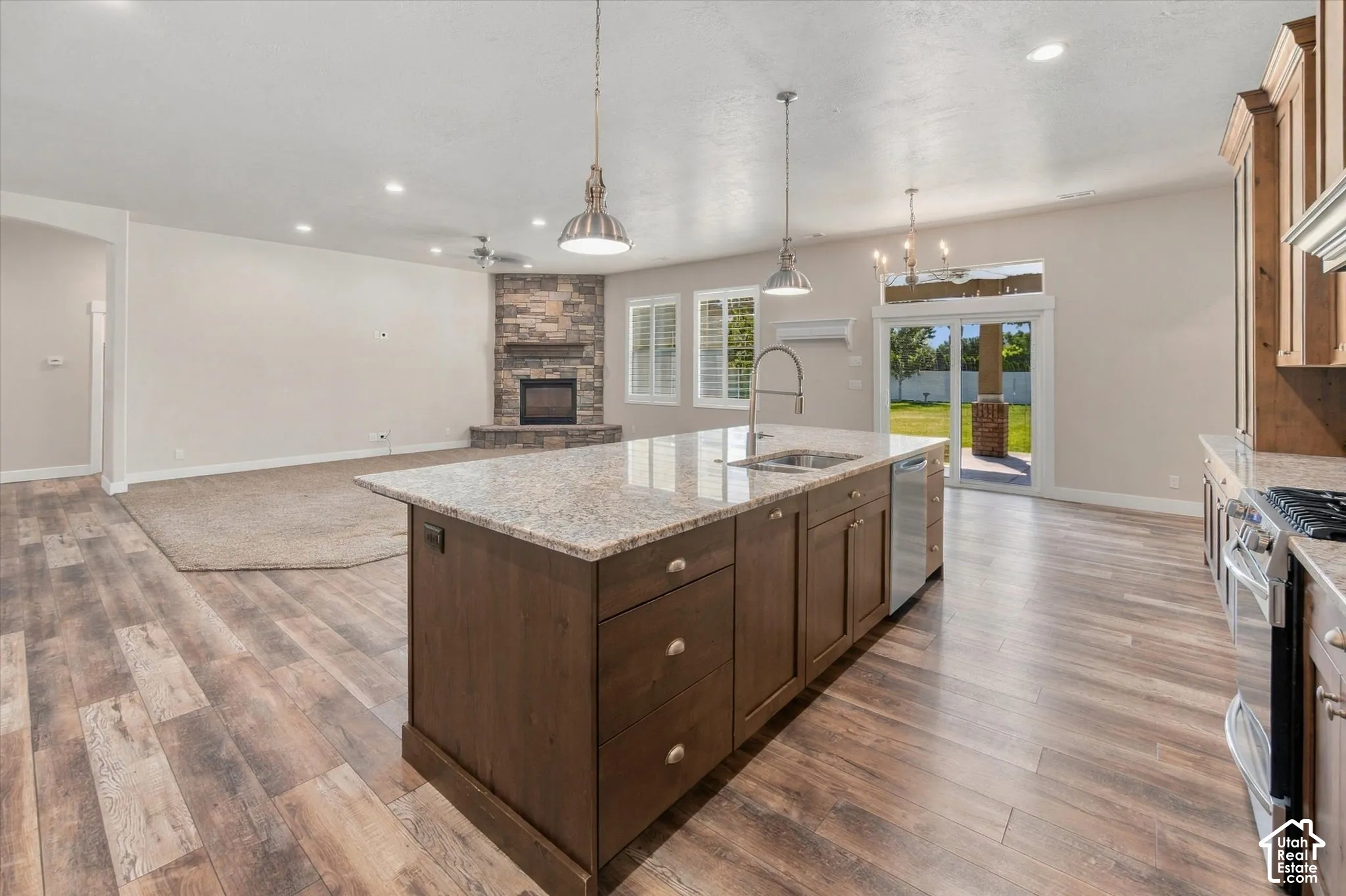 Kitchen island with granite countertop, stainless steel sink, and pendant lighting