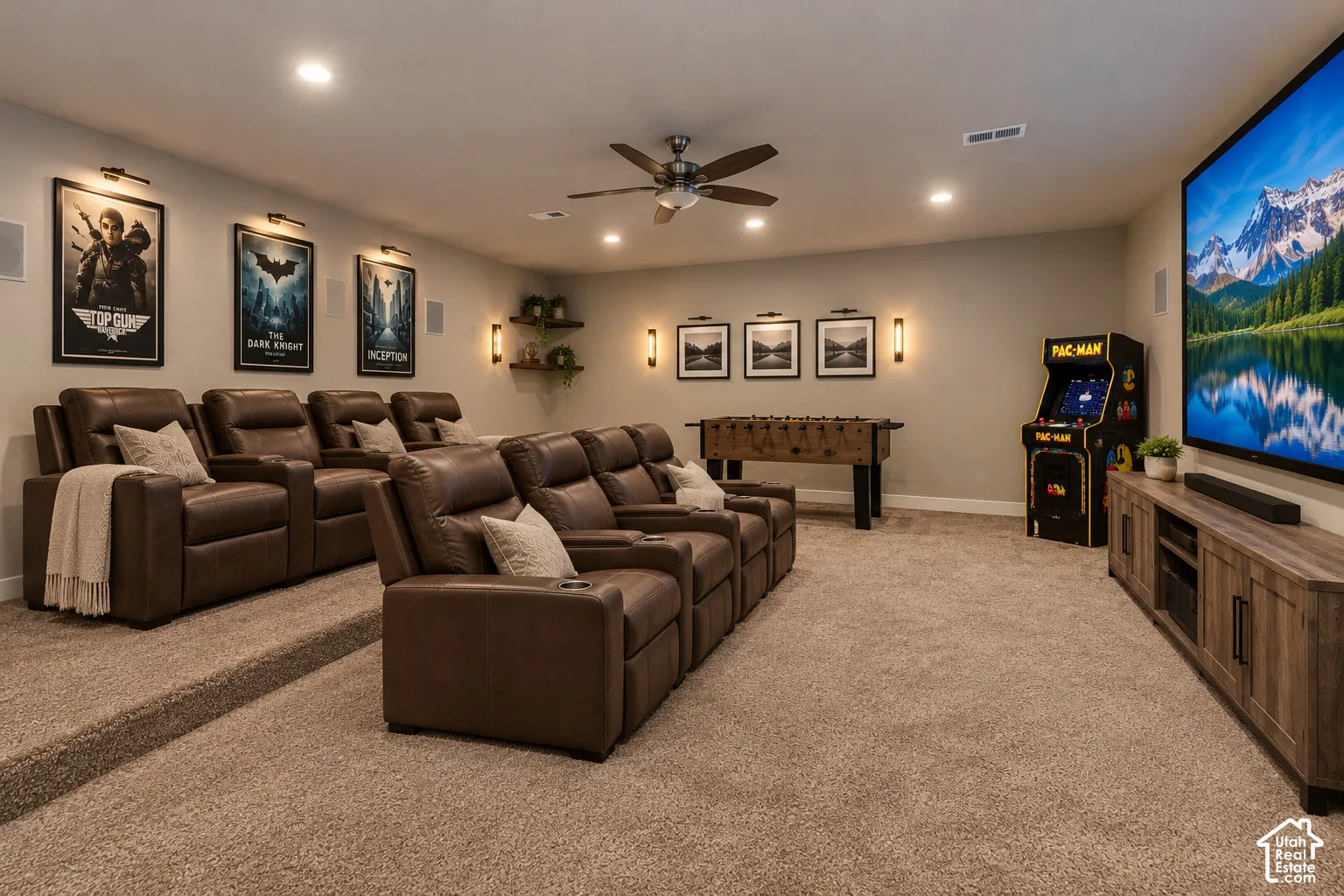 Home Theater and Game RoomMedia room featuring tiered flooring, recessed lighting, ceiling fan, wall-mounted light fixtures, and wall-integrated speakers