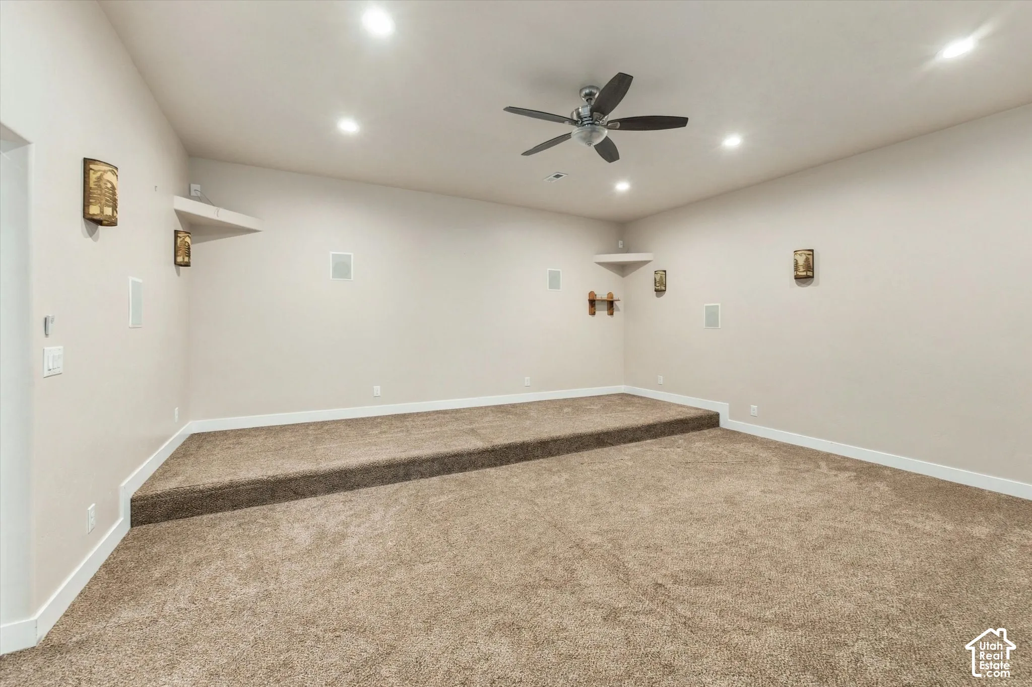 Multi-level carpeted room with recessed lighting and a ceiling fan