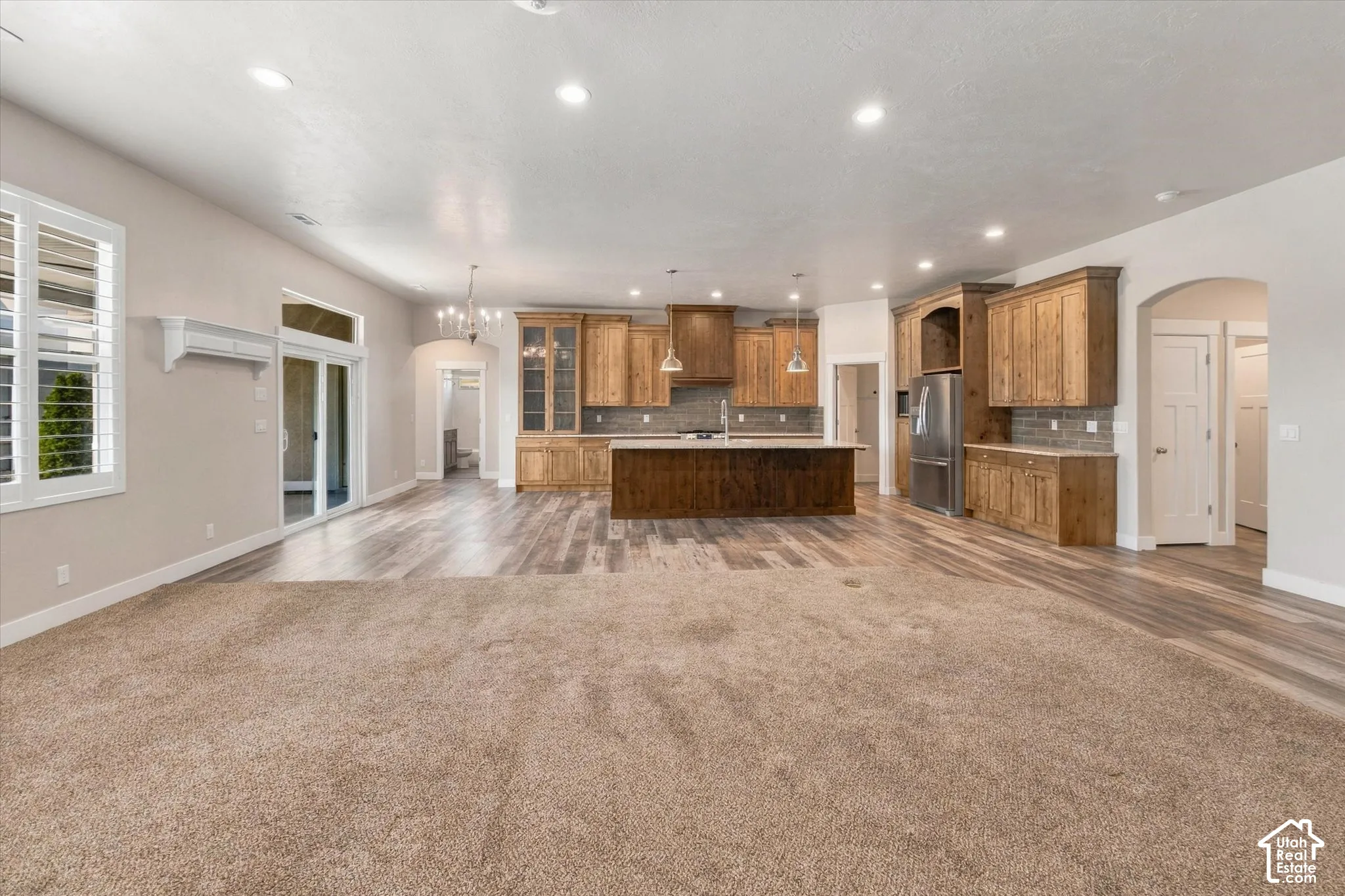 Open concept living area featuring wood-finish flooring, a kitchen island with seating, recessed lighting, and wooden cabinetry