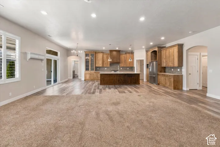 Open concept living area featuring wood-finish flooring, a kitchen island with seating, recessed lighting, and wooden cabinetry