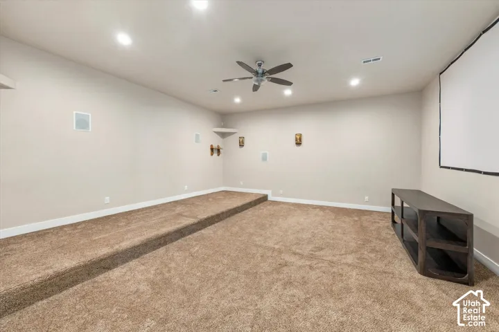 Carpeted room with a raised platform, recessed lighting, and ceiling fan