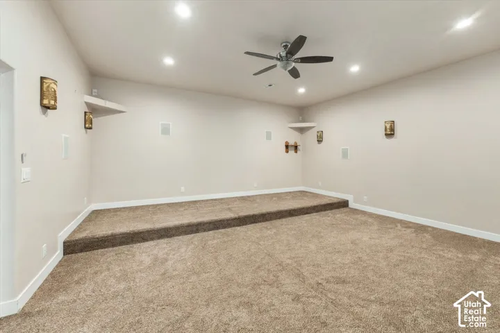 Multi-level carpeted room with recessed lighting and a ceiling fan