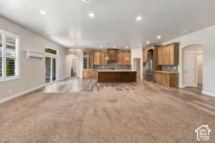 Open concept living area featuring wood-finish flooring, a kitchen island with seating, recessed lighting, and wooden cabinetry