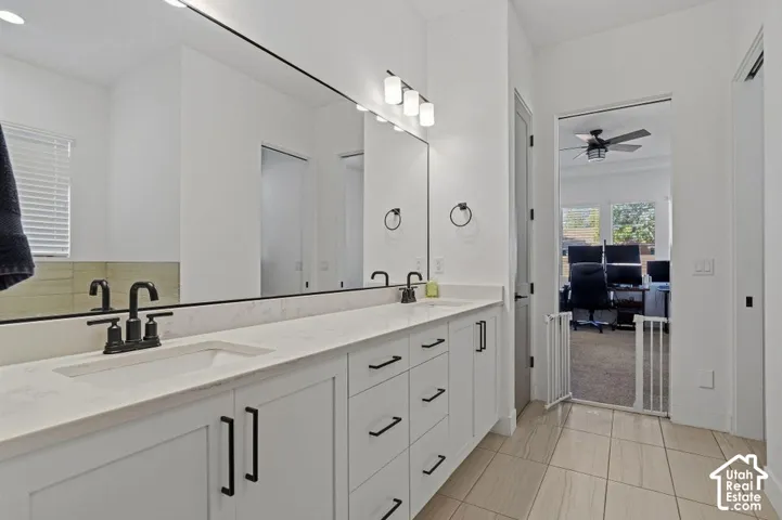Dual vanity with white cabinetry, matte black hardware, and an integrated sink