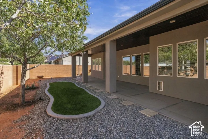 Covered patio with recessed lighting, multiple windows, and a gravel-filled yard with a synthetic turf area