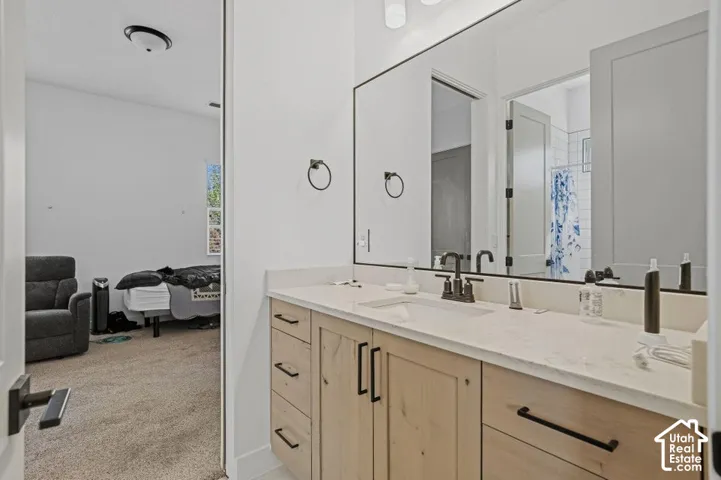 Double vanity with a light-toned countertop, wood-finish cabinetry, integrated sinks, and matte black hardware