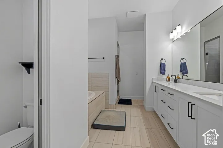 Dual vanity with integrated sinks, modern matte black hardware, large wall mirror, and tile flooring