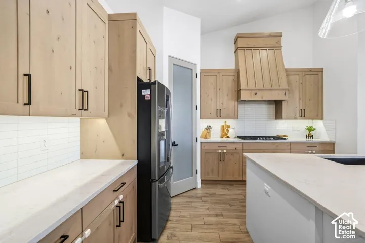 Kitchen featuring wood-finish cabinetry, light-toned countertops, subway tile backsplash, and wood-finish flooring