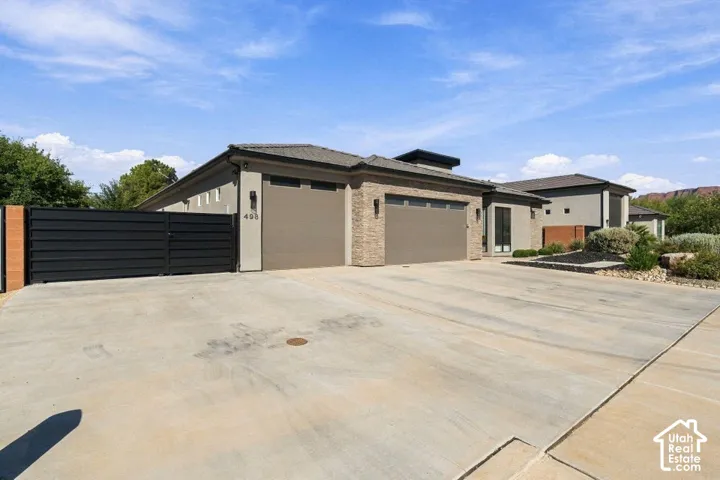 Modern exterior with brick facade accents, multiple garage doors, a flat roofline, and a prominent entry