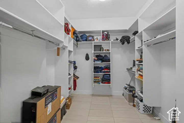 Walk-in closet with extensive built-in shelving, multiple hanging rods, and tile flooring
