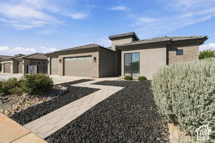 Modern exterior with stucco and stone accents, a structured roofline, and a prominent front entry window