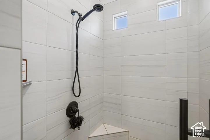 Tiled shower with a handheld showerhead, corner bench, and two transom windows