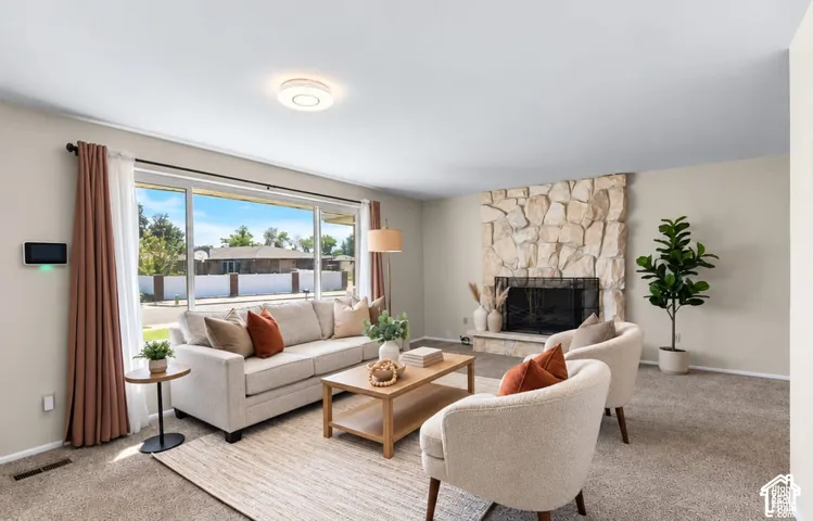 Living area featuring a stone-clad fireplace, large picture window, and recessed ceiling light
