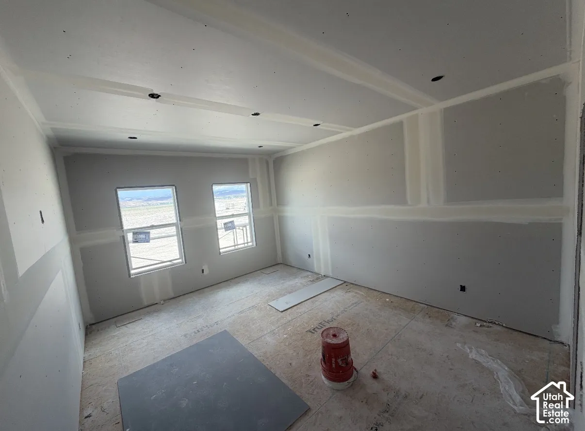 Room under construction featuring two windows, recessed ceiling lights, and unfinished walls