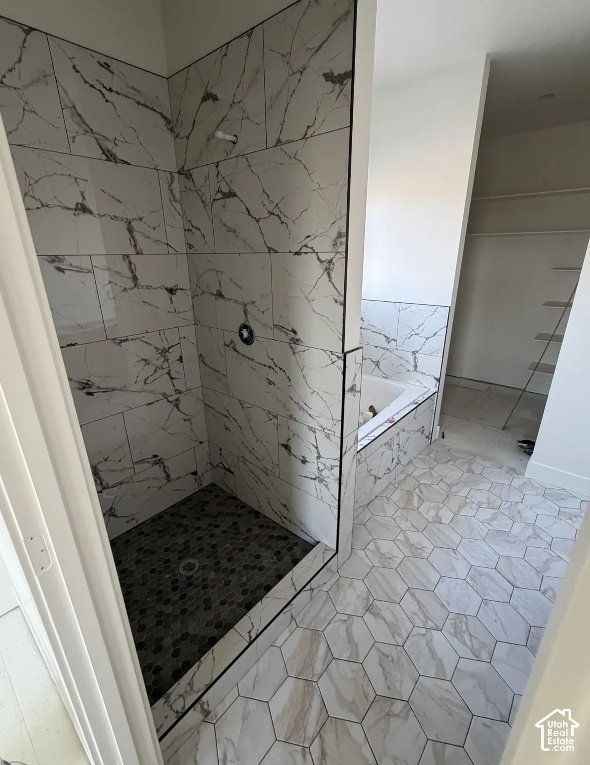 Walk-in shower with large format wall tiling and a pebble-tiled floor