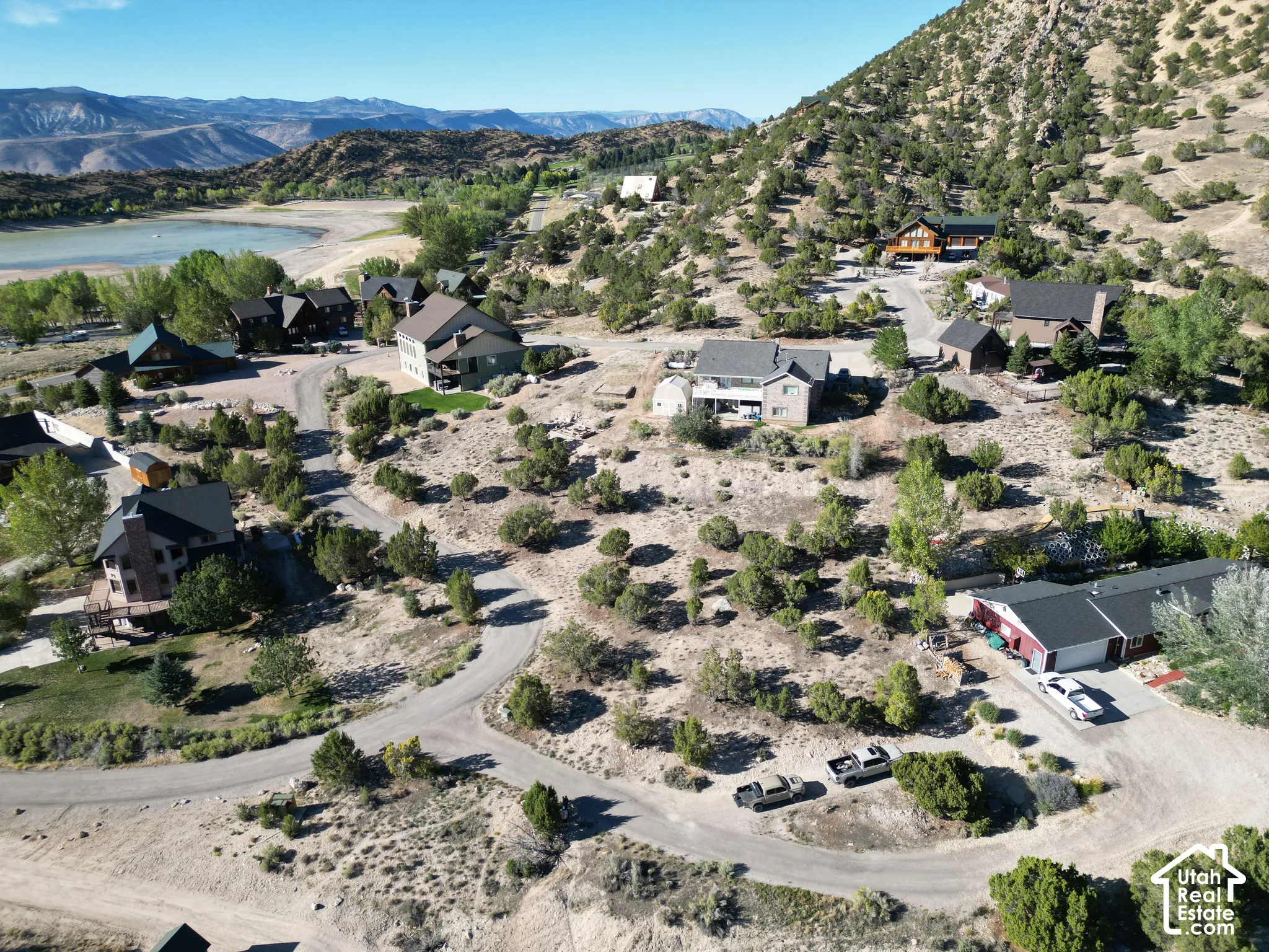 Mountainous terrain with natural vegetation, multiple residential structures, and paved roadways, situated near a body of water