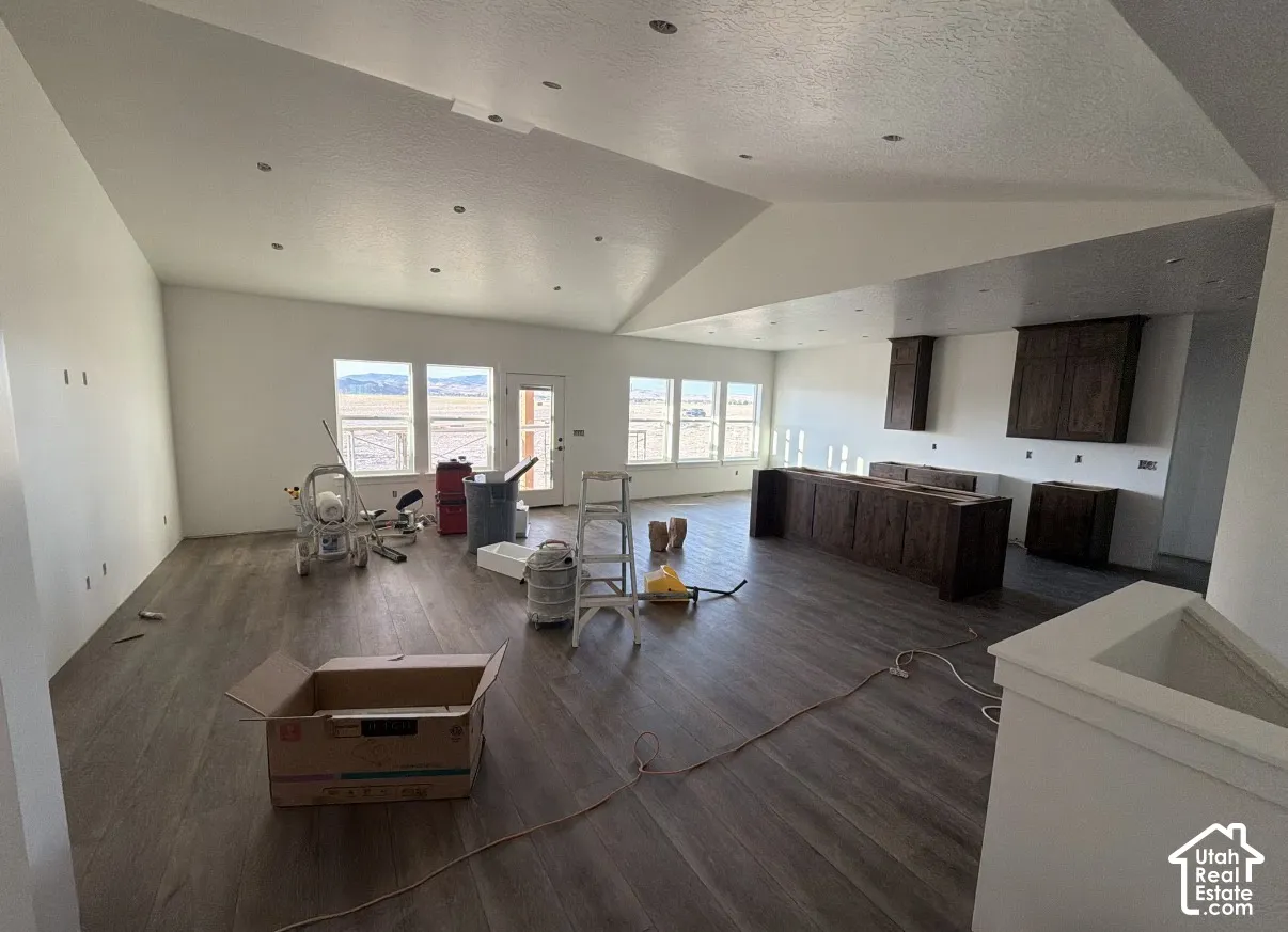 Vaulted ceilings with recessed lighting, wood-finish flooring, multiple windows, and dark wood-finish cabinetry