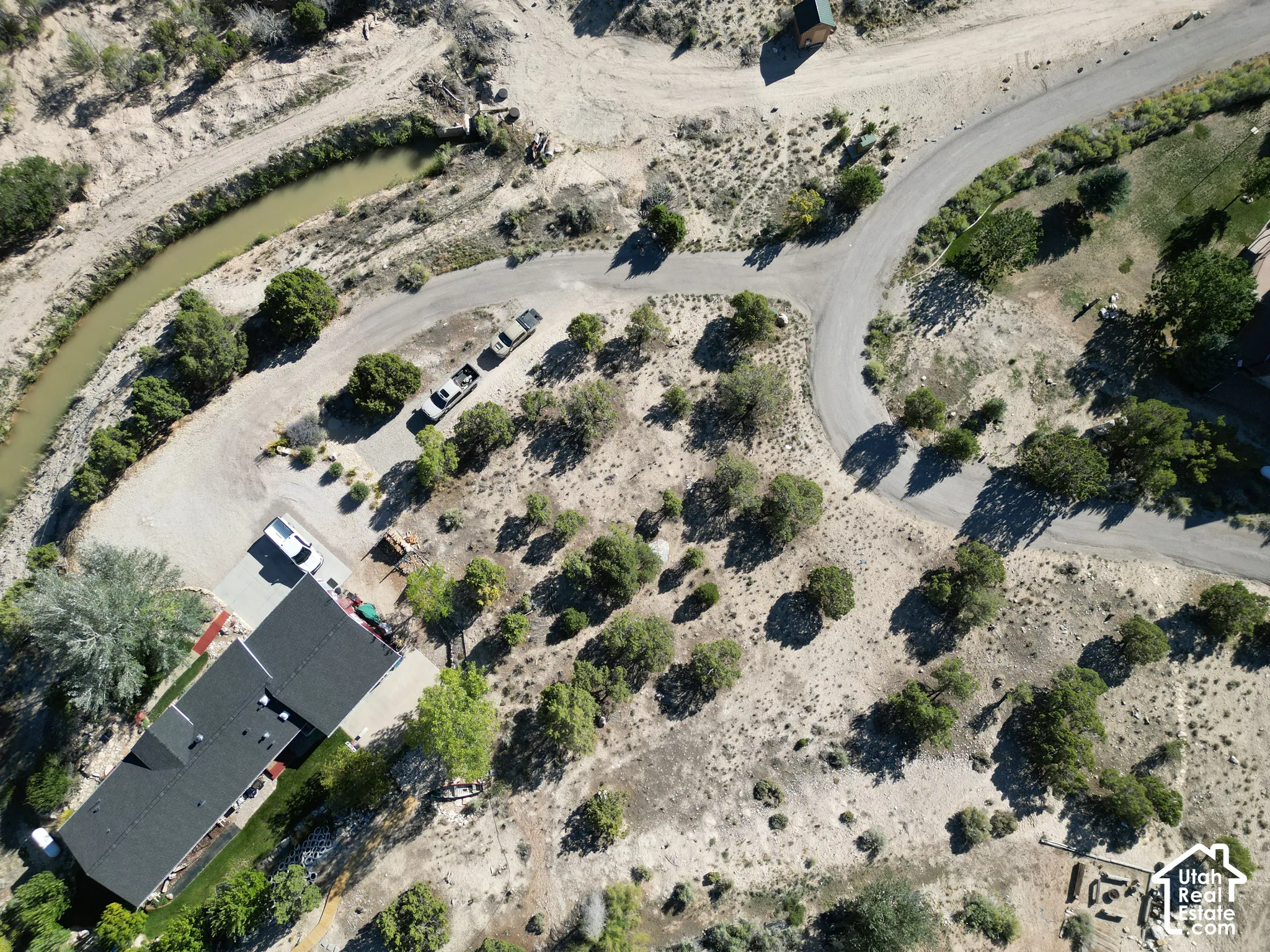 Property with a dark shingle roof, a gravel driveway, and a paved access road