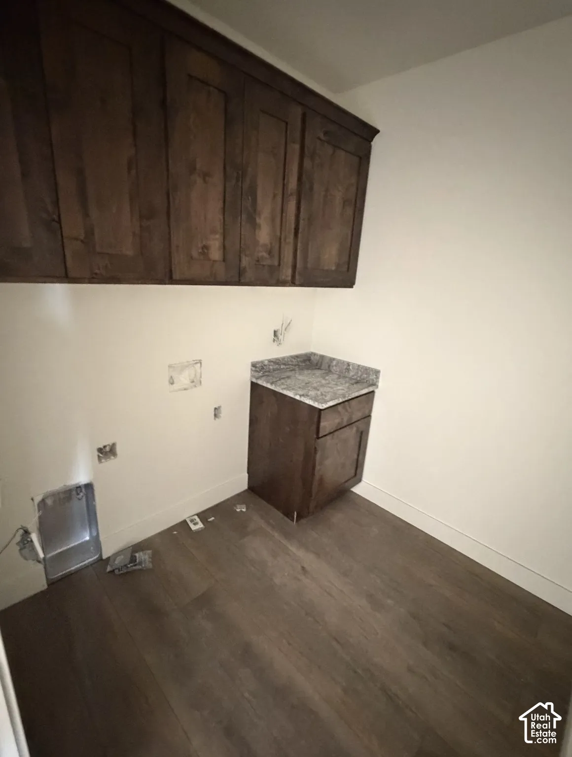 Dark wood-finish cabinetry, wood-finish flooring, and a countertop with a speckled pattern