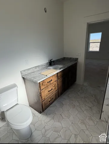 Hexagonal floor tiling, vanity with a rectangular sink, granite countertop, dark wood-finish cabinetry, and a black faucet