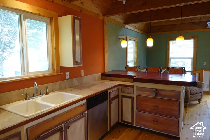 Kitchen featuring wood-finish flooring, exposed wood beams, a double basin sink, and a dishwasher