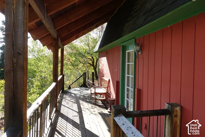 Wood deck with exposed wood railing, red vertical board siding, green trim, and a built-in outdoor light fixture