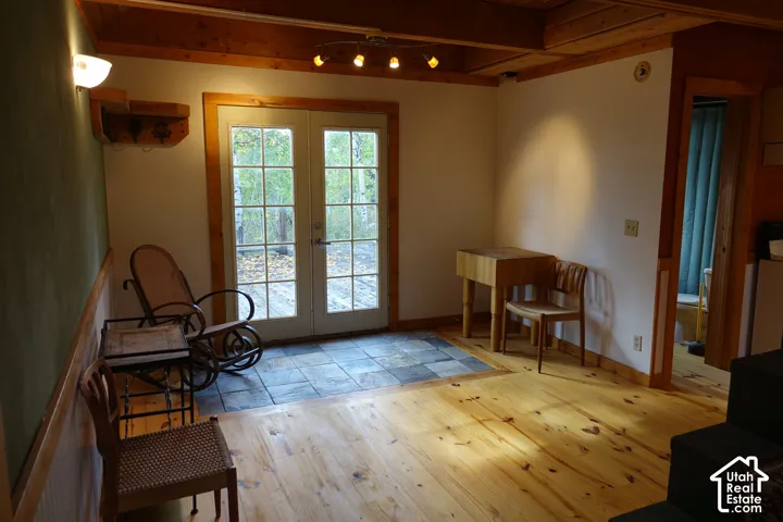 French doors with divided lites, natural wood flooring, exposed wood beam ceiling, track lighting, and a slate tile entry