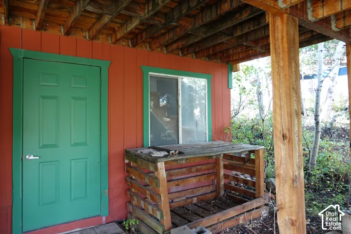 Red exterior siding with a green door, sliding window, and exposed wood beam support
