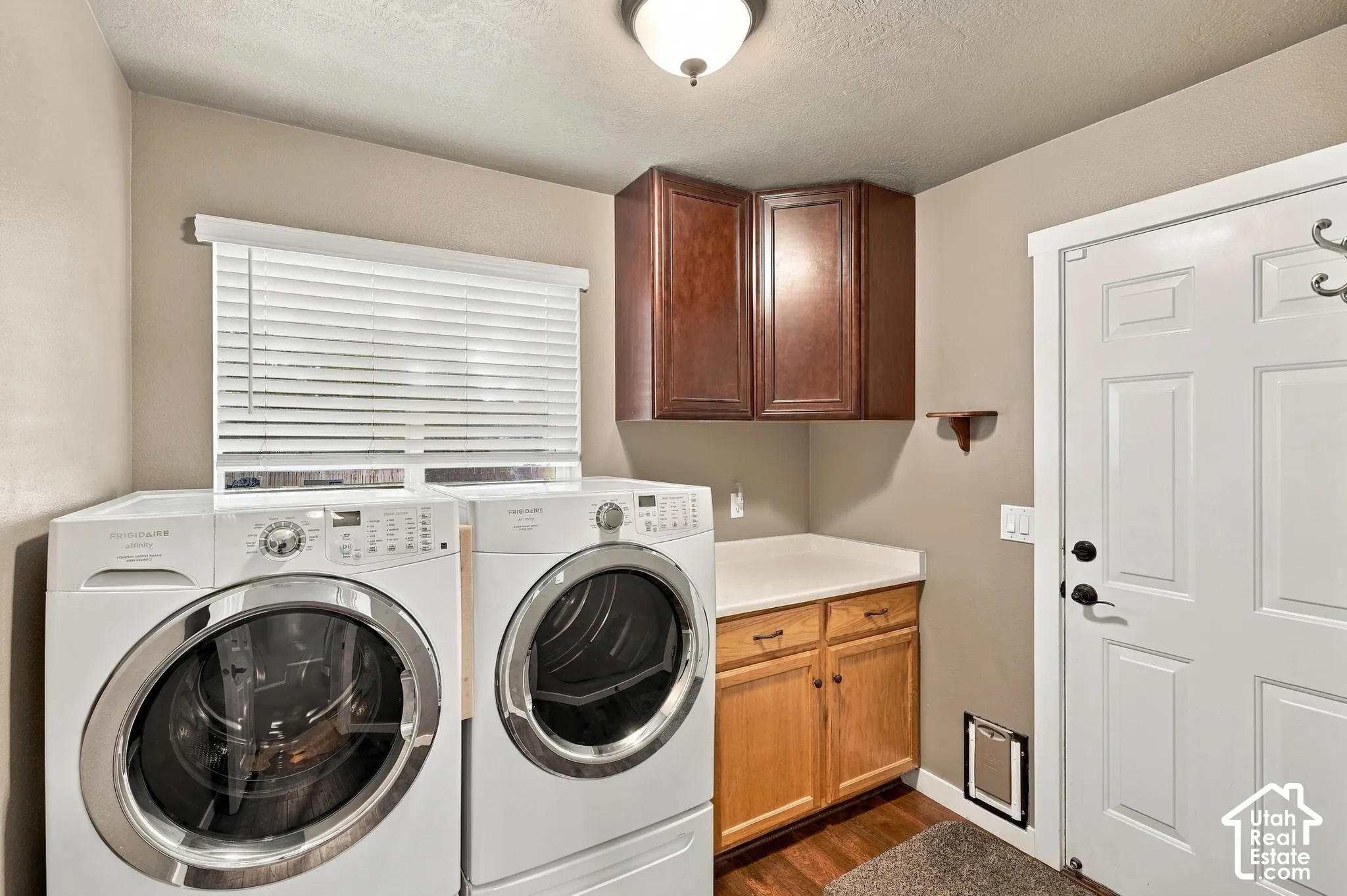 Laundry area with wood-finish flooring, white appliances, and built-in cabinetry