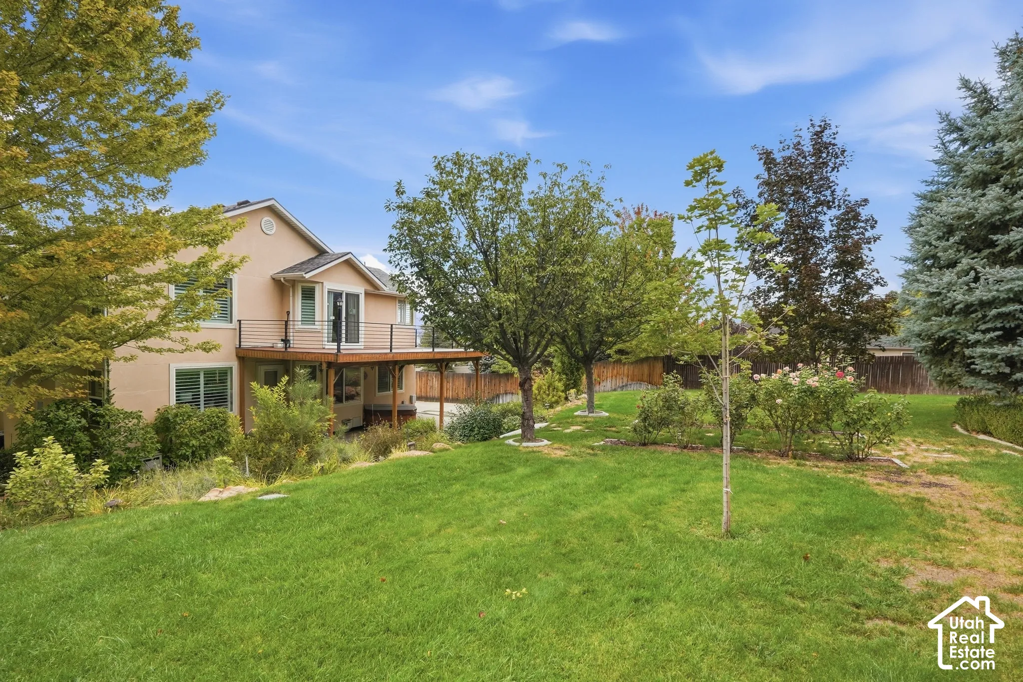 Extensive rear yard with a tiered wood-finish deck, mature trees, and established landscaping