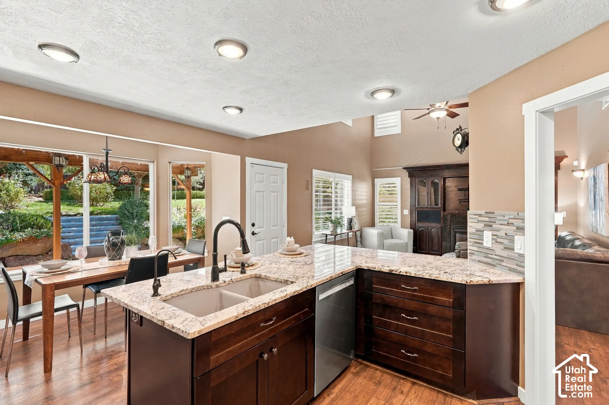 Kitchen island with an undermount double-basin sink, granite countertops, and dark wood cabinetry