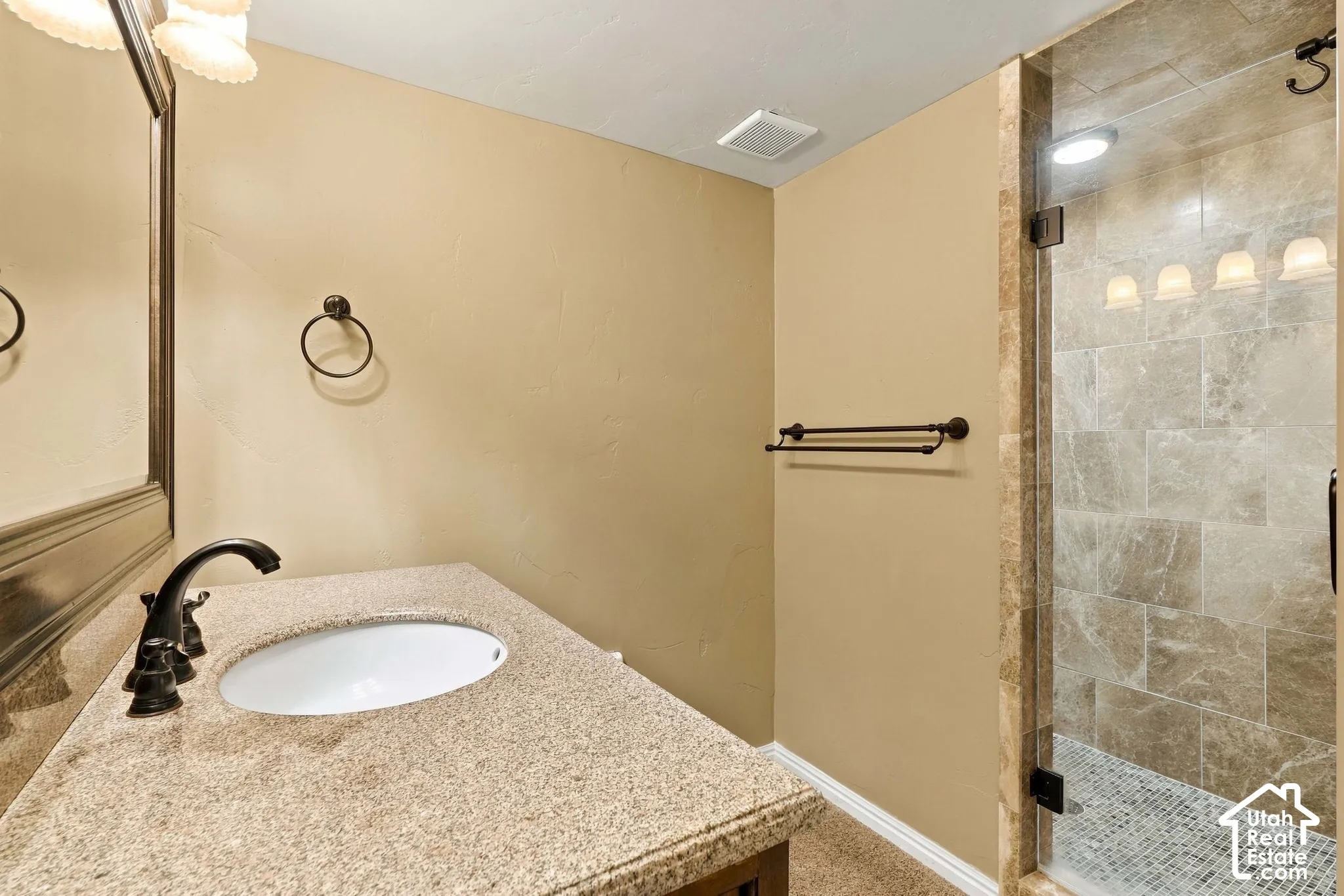 Vanity with a granite-style countertop, undermount sink, and dark bronze-finish faucet