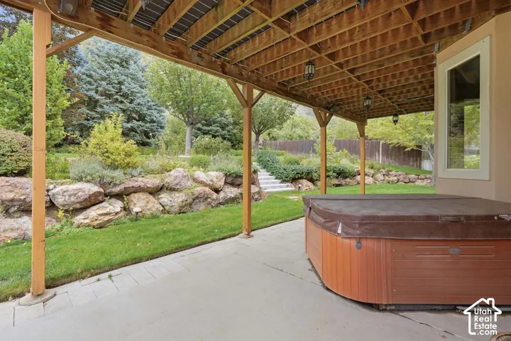 Covered patio with a built-in spa, concrete flooring, and suspended lighting