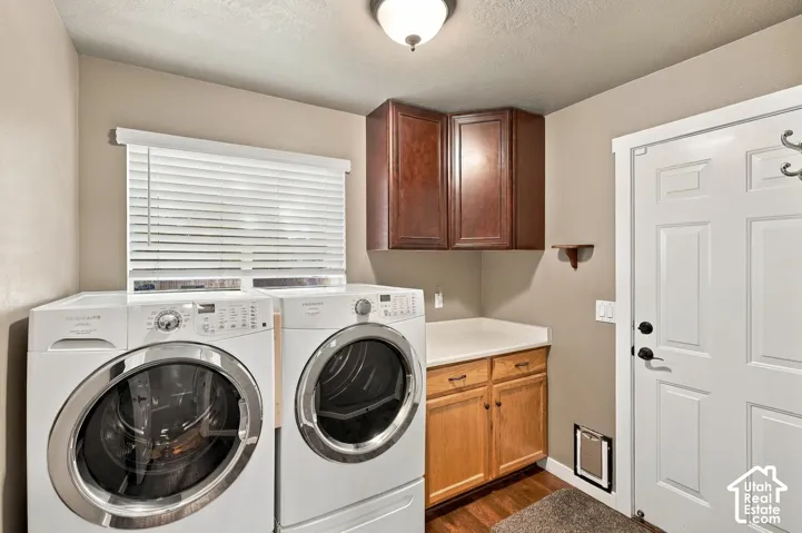 Laundry area with wood-finish flooring, white appliances, and built-in cabinetry