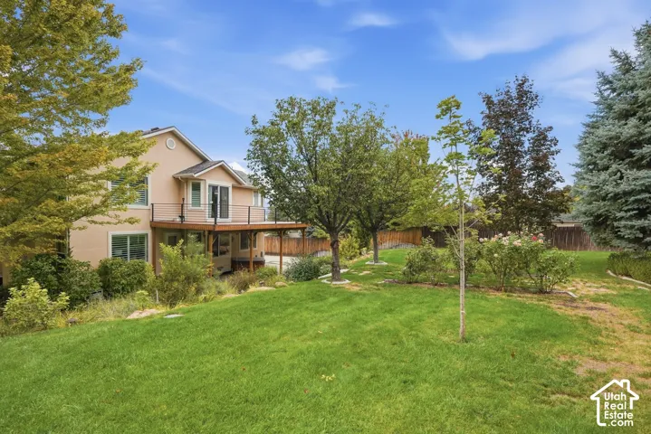 Extensive rear yard with a tiered wood-finish deck, mature trees, and established landscaping