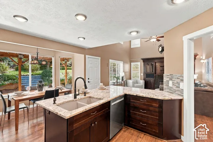 Kitchen island with an undermount double-basin sink, granite countertops, and dark wood cabinetry