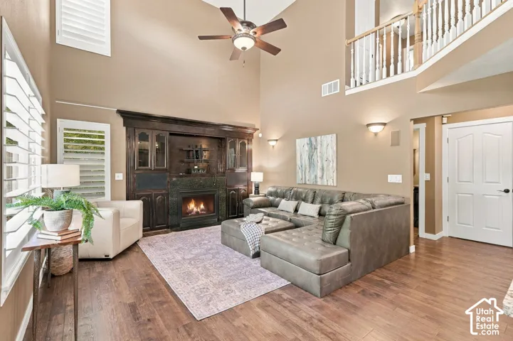 Vaulted ceiling with an integrated ceiling fan, wood-finish flooring, and a built-in media center with a fireplace