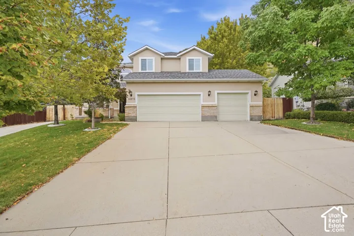Two-story exterior with stucco finish and stone accents, featuring a two-car garage with separate doors, and an additional single-car garage