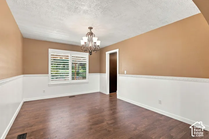 Wood-finish flooring, white wainscoting, and a decorative chandelier