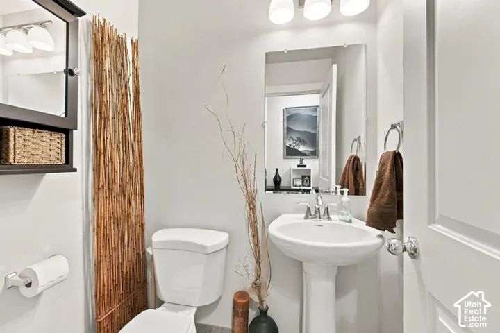 Pedestal sink with chrome faucet, wall-mounted mirror, and overhead vanity lighting