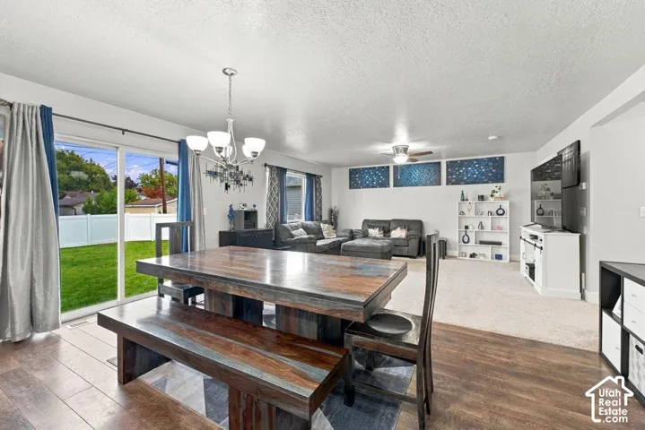 Spacious living area featuring a contemporary chandelier, ceiling fan, and wood-finish flooring
