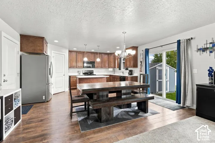 Wood-finish flooring throughout, kitchen featuring wood cabinetry, white countertops, and stainless steel appliances