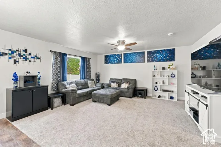 Spacious living area featuring light-colored carpeting and a ceiling fan