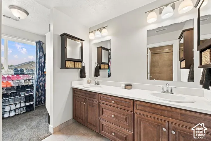 Dual vanity with wood-finish cabinetry, white countertops, and integrated sinks