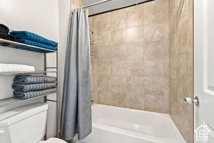 Bathtub with tile surround, white toilet, and chrome door hardware
