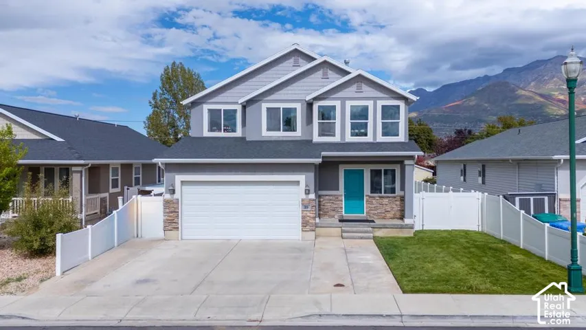 Two-story residence with a light gray exterior, stone accents, and a prominent turquoise entry door