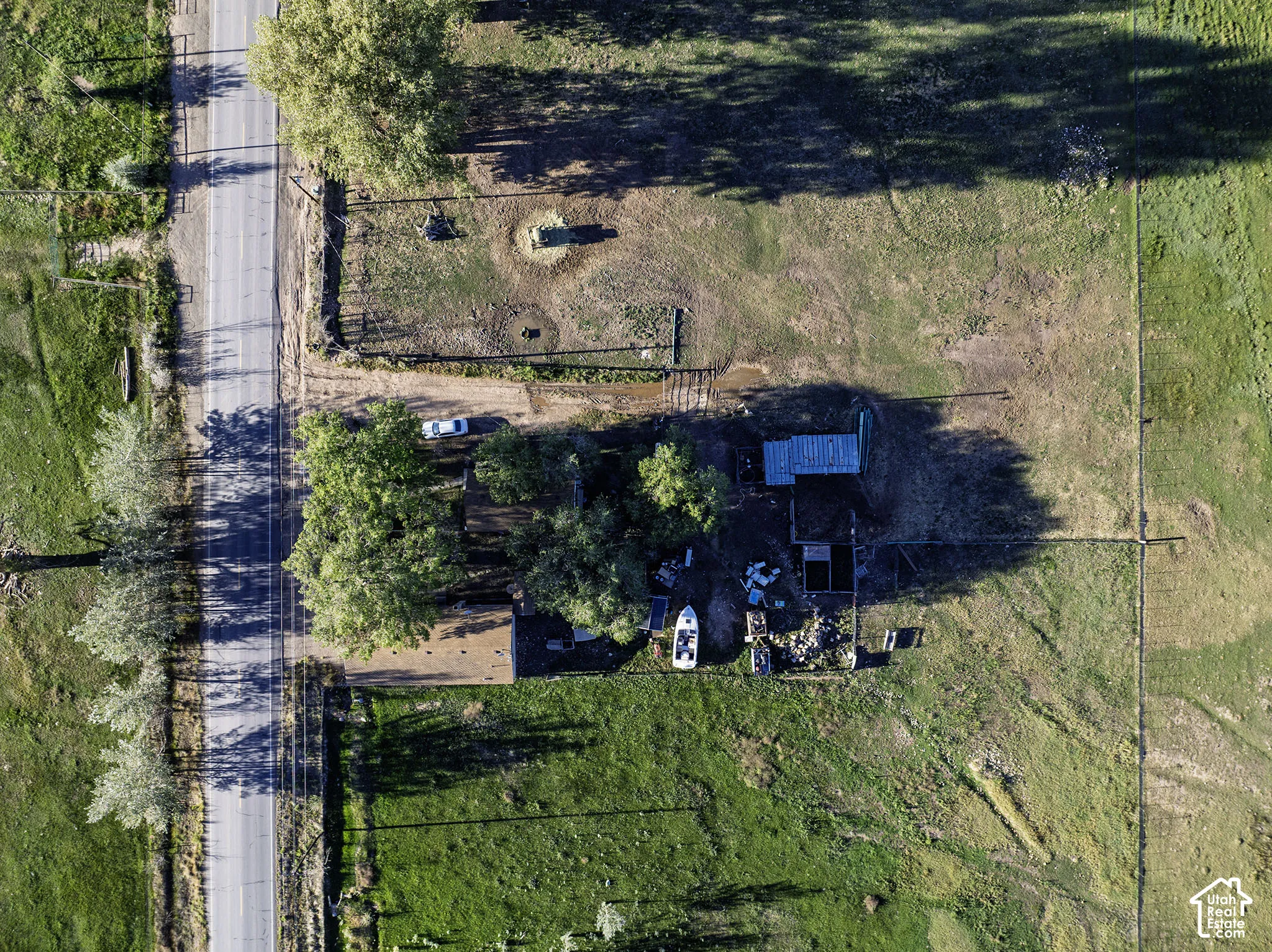 Roadside property with extensive land, mature trees, and a utility structure