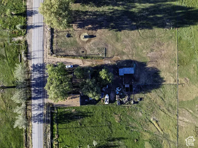 Roadside property with extensive land, mature trees, and a utility structure