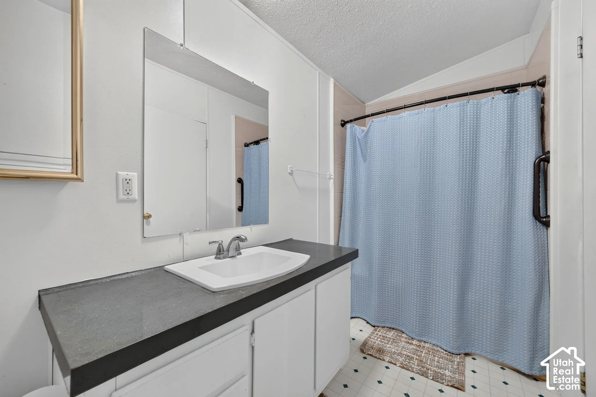 Built-in vanity with a single basin sink, wall-mounted mirror, and tile flooring